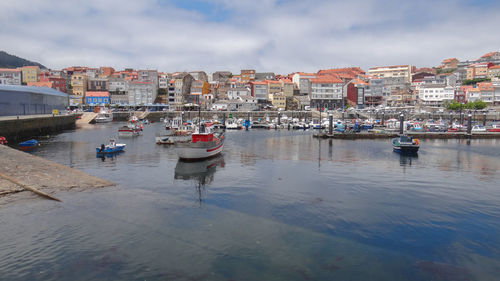 Sailboats moored in sea against buildings in city