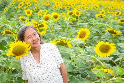 Portrait of woman with sunflower in field