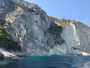 Scenic view of sea and mountains against clear blue sky