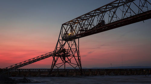 Low angle view of silhouette crane against sky during sunset