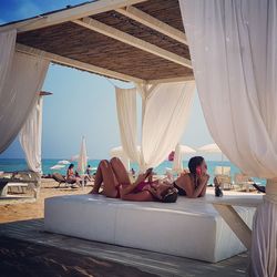 Woman relaxing on beach against sky