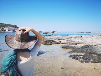 Woman holding umbrella on beach against clear sky