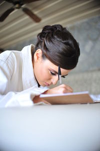 Woman writing in book on table