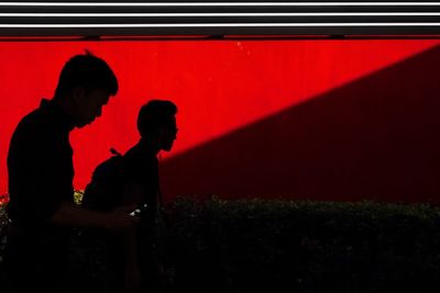 Side view of silhouette couple standing against red wall