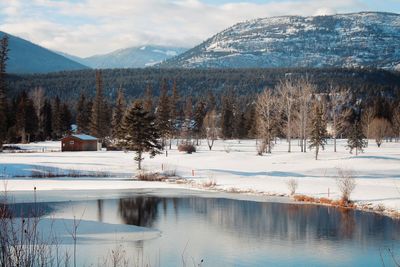 Scenic view of lake by snowcapped mountains against sky