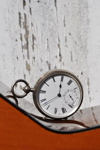 Close-up of pocket watch on guitar against wall