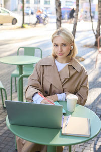 Young woman using laptop while sitting on chair