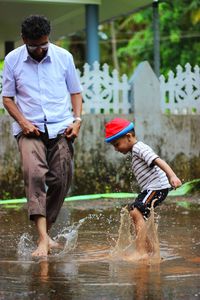 Father and son playing in puddle