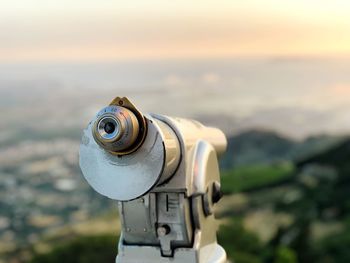 Close-up of coin-operated telescope against sky during sunset