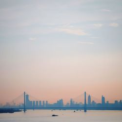 Sea and buildings against sky during sunset