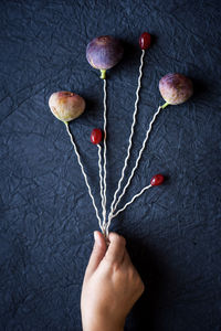 Cropped hand of woman holding threads with figs and berries