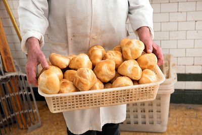 Midsection of man holding buns in basket