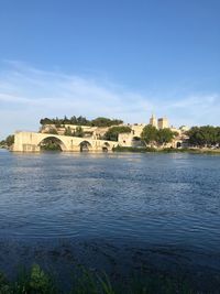 View of buildings by river against sky