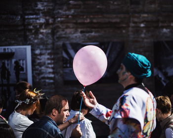 Man holding balloon while walking with crowd in city