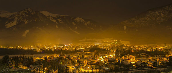 Illuminated townscape against alps during winter at night