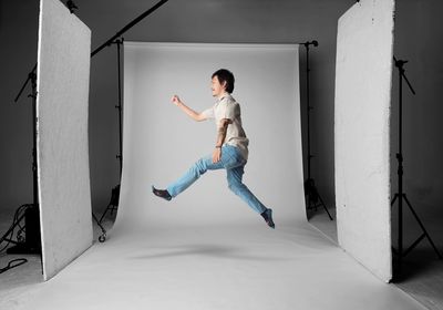 Young man jumping against white backdrop