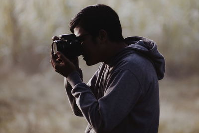 Side view of man photographing outdoors