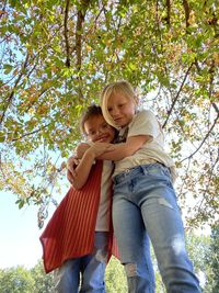 Low angle view of boy standing against trees