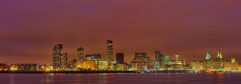 Distant view of west and alexandra towers in illuminated city by lake at night