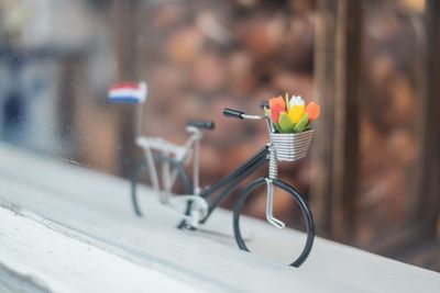 Close-up of toy bicycle on window sill seen through glass