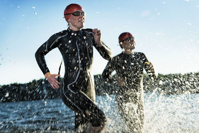 Woman in wetsuit running in sea, sweden