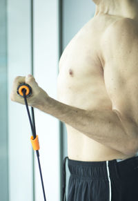 Shirtless man exercising by window