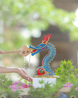 Close-up of woman pouring water from ladle by dragon sculpture