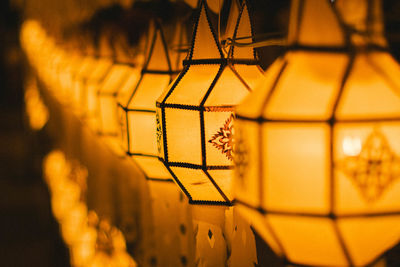 Close-up of yellow lantern hanging on metal fence