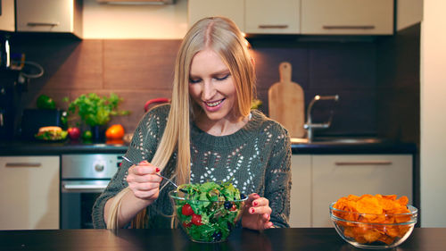 Portrait of young woman holding food at home