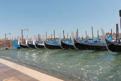 Boats moored in canal against clear blue sky