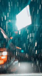 Illuminated street seen through wet glass window