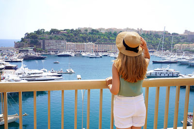 Back view of young woman in monte-carlo looking cityscape and harbor in the principality of monaco.