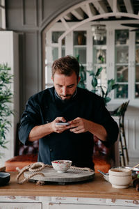 Mid adult man using mobile phone in restaurant