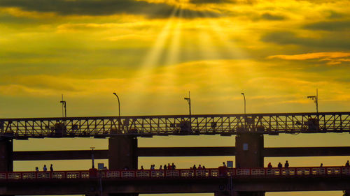 Silhouette bridge against dramatic sky during sunset