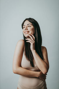 Young woman looking away while standing against gray background