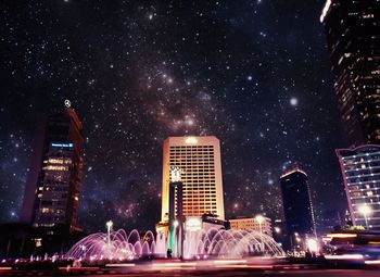 Illuminated buildings in city against sky at night