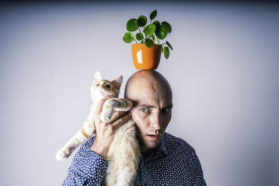 Portrait of man holding cat against white background
