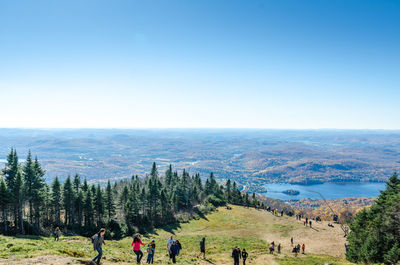 High angle view of people hiking on mountain against blue sky