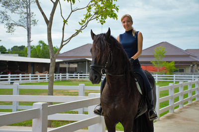 Beautiful young female jockey with blond hair on a black horse. focus on the horse