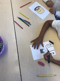 Midsection of children making drawing on table