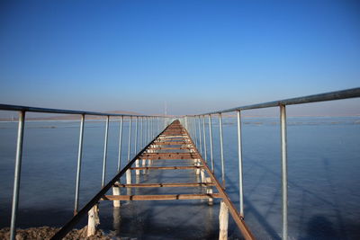 Bridge over sea against clear blue sky