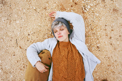 Directly above of young woman lying at beach