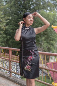 Young woman standing against railing