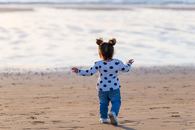 Rear view of girl walking at beach