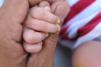 Cropped image of parent holding baby hand