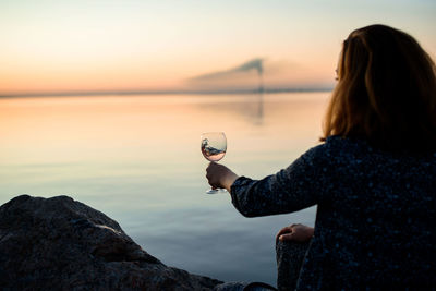 Woman looking at sea against sky during sunset