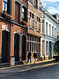 People walking on sidewalk by building in city