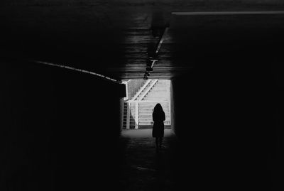 Rear view of man walking in illuminated tunnel
