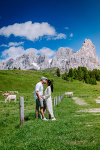 Rear view of couple standing on field against mountains