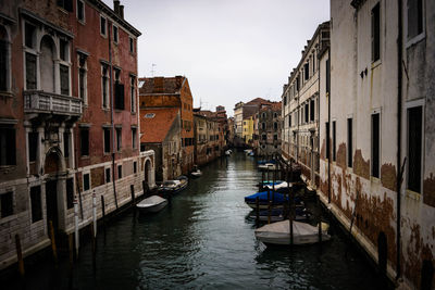 Boats in canal amidst buildings in city